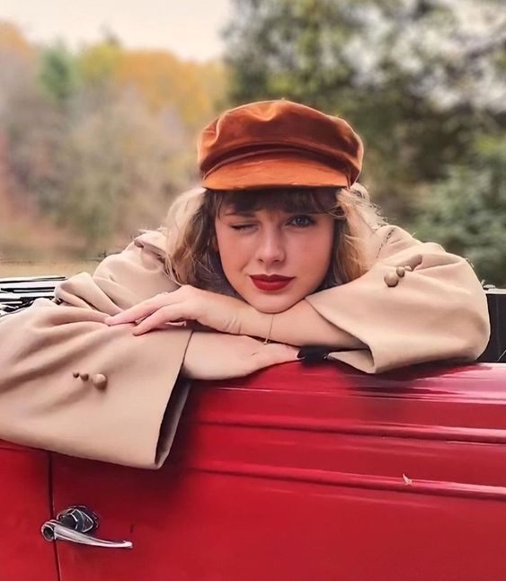 Taylor Swift usando um chapéu vermelho e piscando com o olho direito.